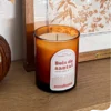 Bougie parfumée bois de santal en verre ambré, posée sur une étagère en bois dans une décoration naturelle et chaleureuse.