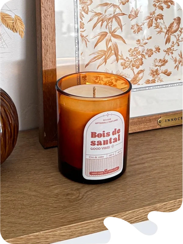 Bougie parfumée bois de santal en verre ambré, posée sur une étagère en bois dans une décoration naturelle et chaleureuse.