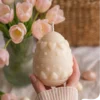 Bougie décorative en forme d’œuf de Pâques avec motifs cœurs, ambiance printanière avec tulipes roses.