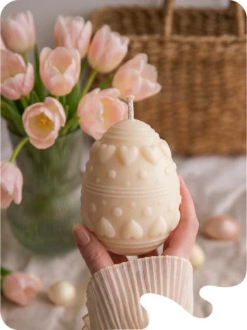 Bougie décorative en forme d’œuf de Pâques avec motifs cœurs, ambiance printanière avec tulipes roses.