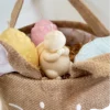 Panier en toile de jute en forme de lapin contenant des bougies artisanales en forme d’œufs et de lapin. Idée cadeau originale pour Pâques.