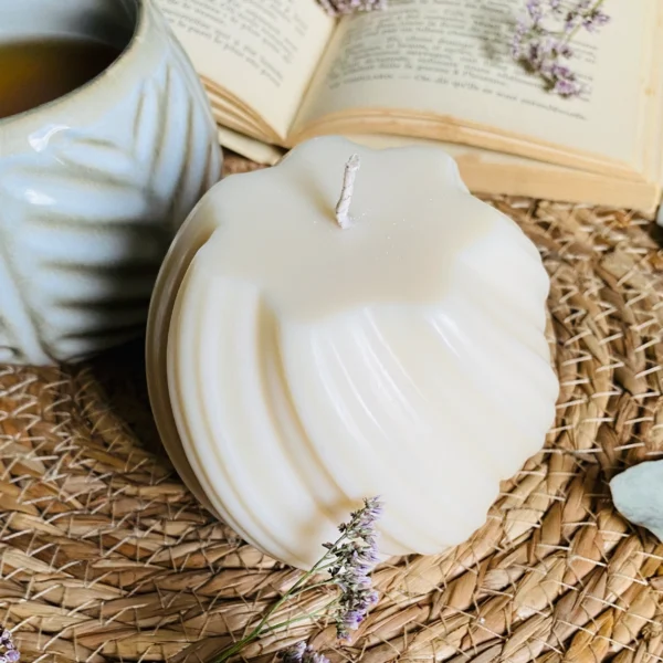 Bougie décorative en forme de spirale, posée sur un tapis en fibres naturelles, ambiance relaxante avec un mug en céramique et un livre ouvert en arrière-plan.