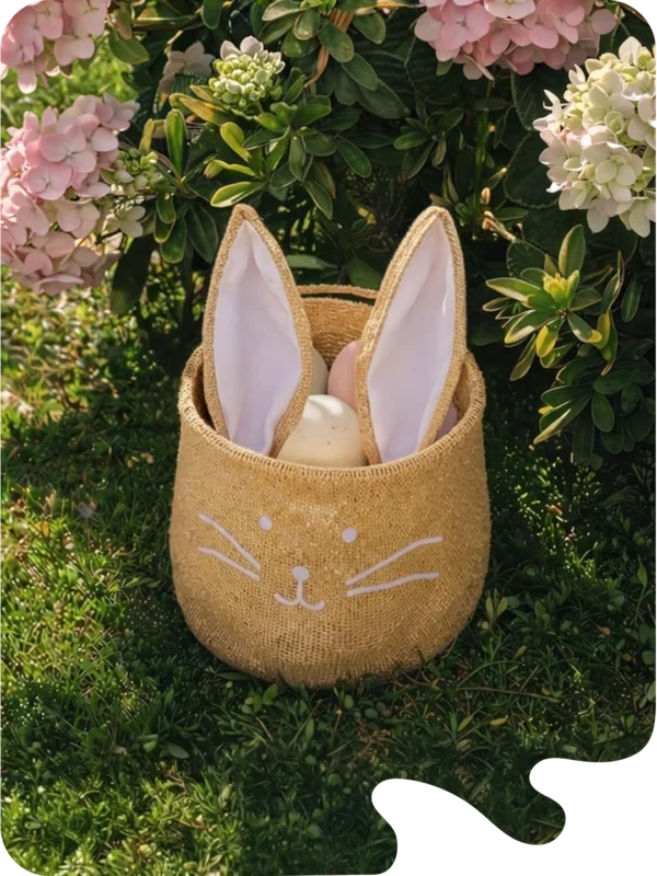 Panier décoratif en forme de lapin en tissu beige avec oreilles roses, ambiance printanière fleurie.