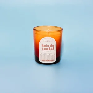 Bougie artisanale parfumée Bois de Santal dans un verre ambré, sur fond bleu – Une touche boisée et apaisante pour votre intérieur.