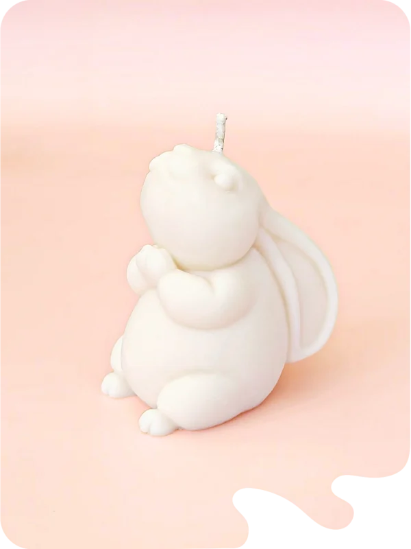 Bougie artisanale en forme de lapin, couleur blanche, sur fond rose. Une touche poétique et apaisante pour votre intérieur.