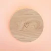 Support rond en bois naturel avec cœur gravé, conçu pour accueillir bougies décoratives ou parfumées, présenté sur fond pastel.