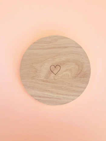 Support rond en bois naturel avec cœur gravé, conçu pour accueillir bougies décoratives ou parfumées, présenté sur fond pastel.