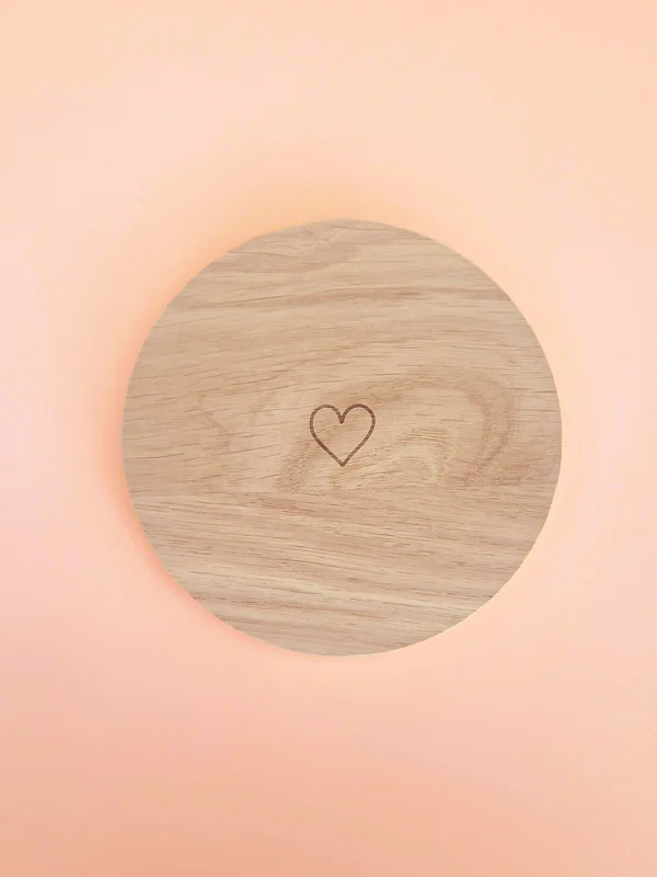 Support rond en bois naturel avec cœur gravé, conçu pour accueillir bougies décoratives ou parfumées, présenté sur fond pastel.