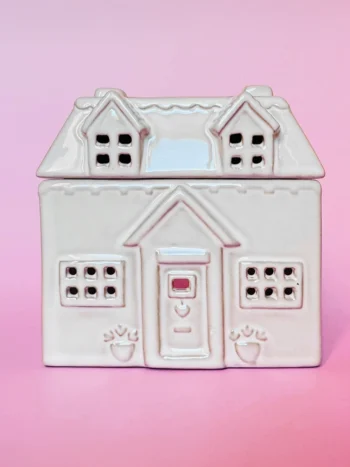Brûle-parfum Cottage - Vue de face | Crème Brûlée Bougies Brûle-parfum en céramique en forme de maison cottage, vue de face, avec des détails sculptés, fenêtres et porte ajourées.