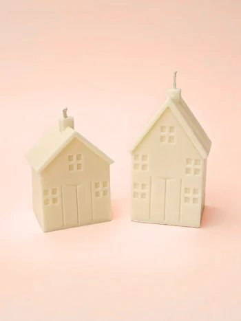 Duo de bougies décoratives en forme de maison, tailles M et S, fabriquées en cire végétale naturelle. Parfaites pour une décoration cosy et minimaliste sur fond bleu pastel.