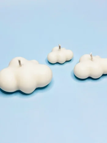 Bougies décoratives en forme de nuages, fabriquées en cire naturelle, disposées sur un fond bleu ciel.