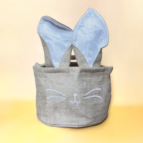 Panier en toile de jute grise avec oreilles de lapin doublées de tissu bleu et motif visage de lapin brodé – Parfait pour les fêtes de Pâques ou comme rangement décoratif.