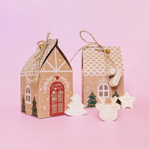 Pack de 6 fondants parfumés en forme de sapin, étoile et renne, présentés dans des maisons en carton décorées pour Noël.