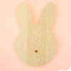 Support en bois naturel en forme de lapin avec petit cœur gravé, conçu pour accueillir bougies décoratives, fondants ou petits accessoires déco, sur fond pastel.