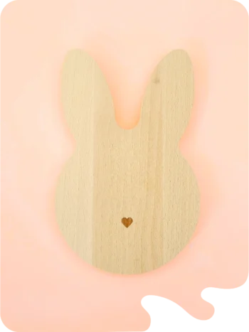 Support en bois naturel en forme de lapin avec petit cœur gravé, conçu pour accueillir bougies décoratives, fondants ou petits accessoires déco, sur fond pastel.