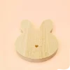 Support en bois naturel en forme de tête de lapin avec petit cœur gravé, conçu pour accueillir bougies décoratives, fondants ou accessoires déco, sur fond pastel.
