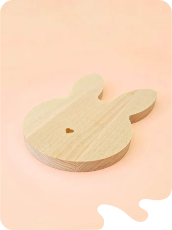 Support en bois naturel en forme de lapin allongé avec petit cœur gravé, idéal pour bougies décoratives, fondants parfumés ou accessoires déco, sur fond pastel.
