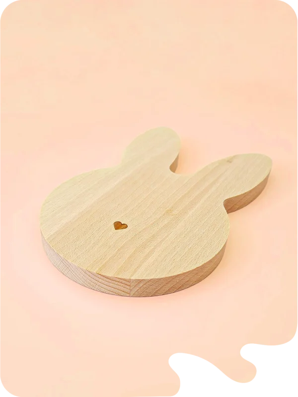 Support en bois naturel en forme de lapin allongé avec petit cœur gravé, idéal pour bougies décoratives, fondants parfumés ou accessoires déco, sur fond pastel.
