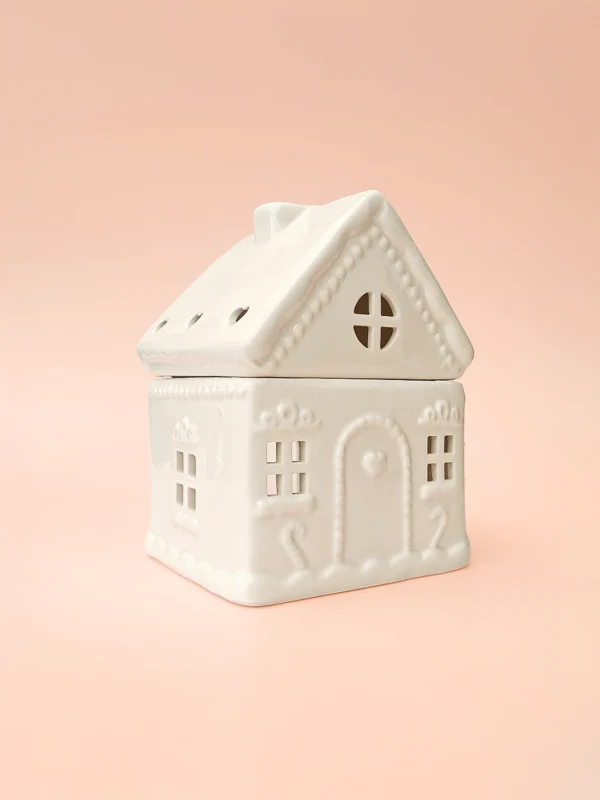 Brûle-parfum Sugar House en céramique blanche, design maison de pain d’épices, vue de trois-quarts sur fond rose.