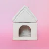 Brûle-parfum Sugar House en céramique blanche, vue arrière avec ouverture pour insérer une bougie chauffe-plat, sur fond rose.