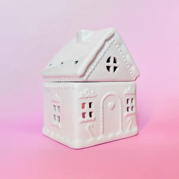 Brûle-parfum Sugar House en céramique blanche, design maison de pain d’épices, vue de trois-quarts sur fond rose.