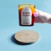 Support en bois gravé d’un cœur avec une bougie parfumée Crème Brûlée en cire de colza, ambiance chaleureuse et artisanale.