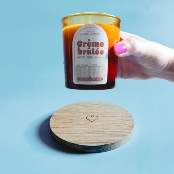 Support en bois gravé d’un cœur avec une bougie parfumée Crème Brûlée en cire de colza, ambiance chaleureuse et artisanale.