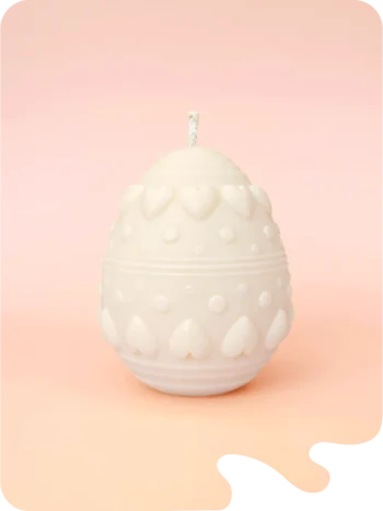 Bougie décorative en forme d’œuf avec motifs cœurs et reliefs, en cire naturelle, présentée sur fond pastel.
