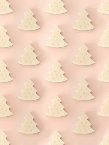 Fondants Forest | Bois de Santal Fondants parfumés Forest en forme de sapin, parfum bois de santal, présentés en motif répétitif sur un fond rose pastel.