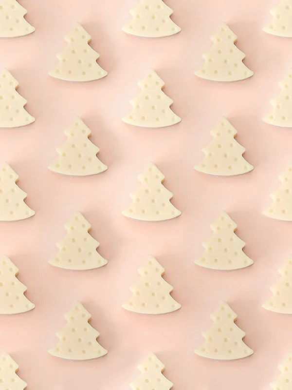 Fondants parfumés Forest en forme de sapin, parfum bois de santal, présentés en motif répétitif sur un fond rose pastel.