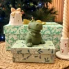 Bougie décorative verte en forme de dinosaure Roooaar, posée sur des boîtes cadeaux devant un sapin de Noël.