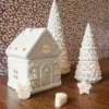 Brûle-parfum Sugar House en céramique blanche, présenté avec des sapins décoratifs dans une ambiance de Noël chaleureuse.
