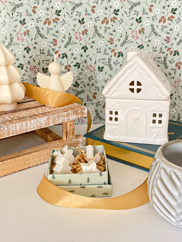 Brûle-parfum Sugar House en céramique blanche, présenté avec des décorations de Noël et une boîte de fondants parfumés.