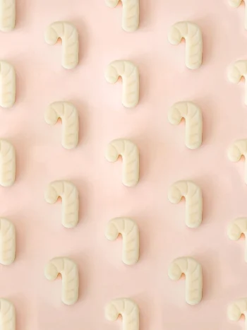 Fondants Sugar Rush | Cannelle Fondants parfumés Sugar Rush en forme de sucre d’orge, parfum cannelle, présentés en motif répétitif sur un fond rose pastel.