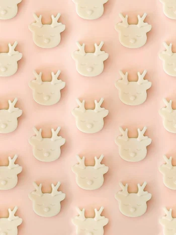 Fondants parfumés Wild Wild Melt en forme de tête de renne, parfum ambre, présentés en motif répétitif sur un fond rose pastel.